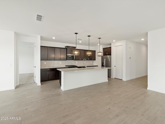 17703 W Southgate Ave, Goodyear, AZ 85338 - kitchen featuring visible vents, stainless steel fridge with ice dispenser, dark brown cabinetry, light wood-style floors, and tasteful backsplash