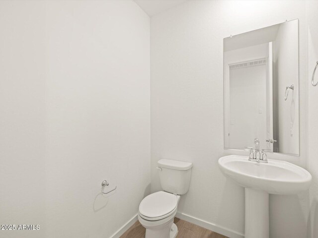 17703 W Southgate Ave, Goodyear, AZ 85338 - half bathroom with toilet, baseboards, and wood finished floors