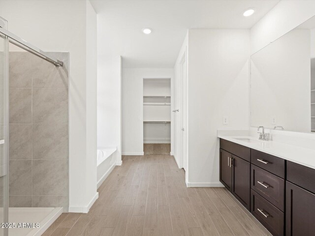 17703 W Southgate Ave, Goodyear, AZ 85338 - bathroom with a spacious closet, a shower stall, wood finished floors, a bath, and vanity