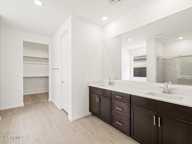 17703 W Southgate Ave, Goodyear, AZ 85338 - bathroom featuring a shower stall, wood finished floors, double vanity, and a sink