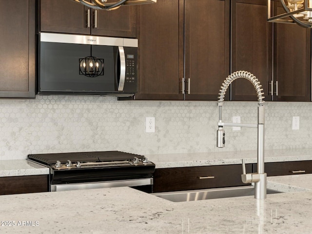 17703 W Southgate Ave, Goodyear, AZ 85338 - kitchen featuring tasteful backsplash, dark brown cabinetry, appliances with stainless steel finishes, a notable chandelier, and a sink
