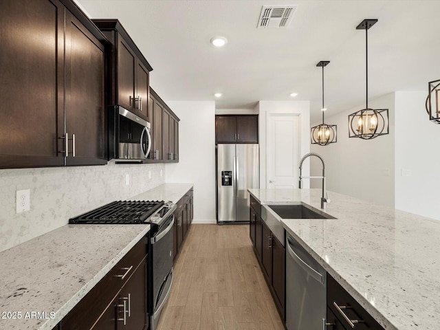17703 W Southgate Ave, Goodyear, AZ 85338 - kitchen featuring visible vents, light wood-style flooring, a sink, appliances with stainless steel finishes, and light stone countertops