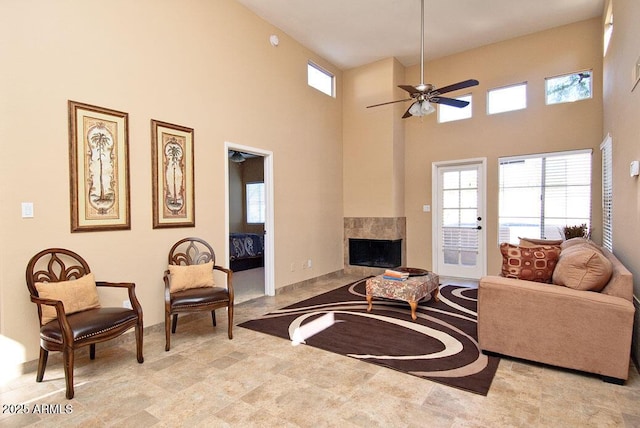 living room with ceiling fan, a multi sided fireplace, and a high ceiling