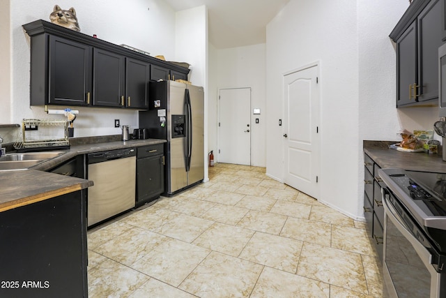 kitchen featuring stainless steel appliances, dark countertops, a sink, and dark cabinets