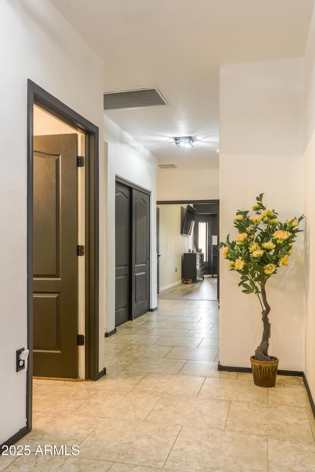 hall featuring visible vents and baseboards