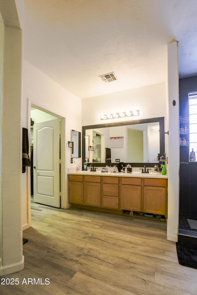 bathroom featuring double vanity, a sink, visible vents, and wood finished floors