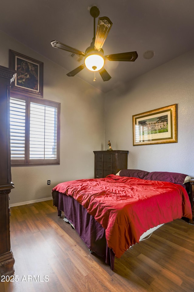 bedroom featuring a ceiling fan, baseboards, and wood finished floors