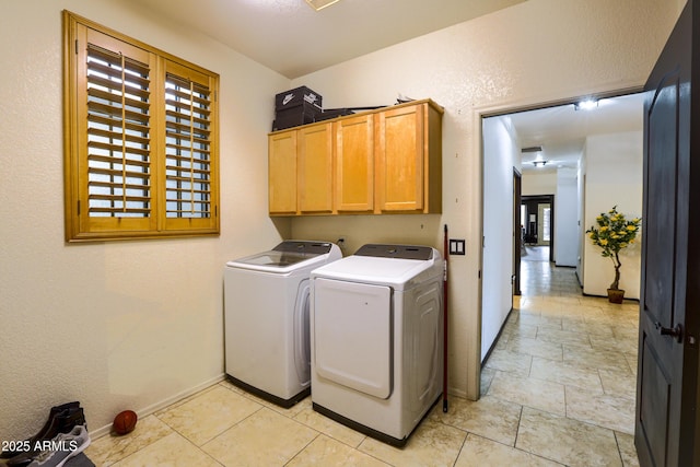 clothes washing area featuring baseboards, cabinet space, and washer and dryer