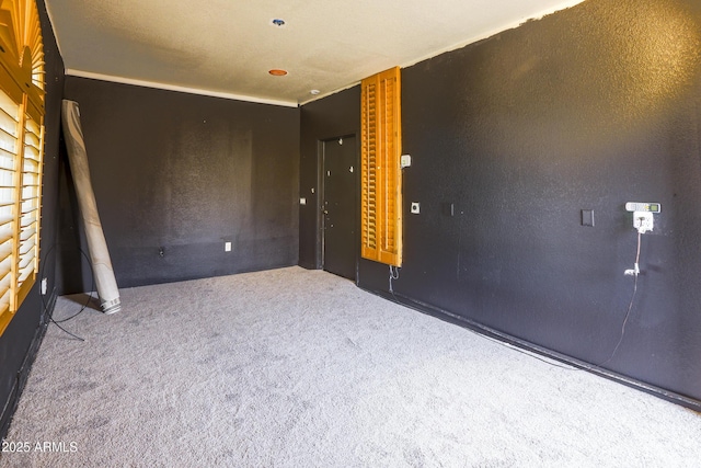 carpeted empty room featuring a textured wall