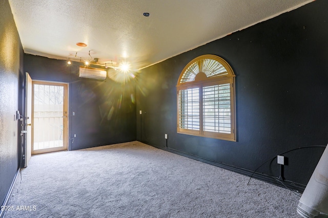 empty room with carpet floors, a textured ceiling, and a wall mounted AC