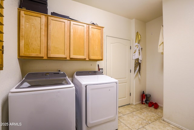 laundry area with light tile patterned flooring, washing machine and clothes dryer, cabinet space, and baseboards