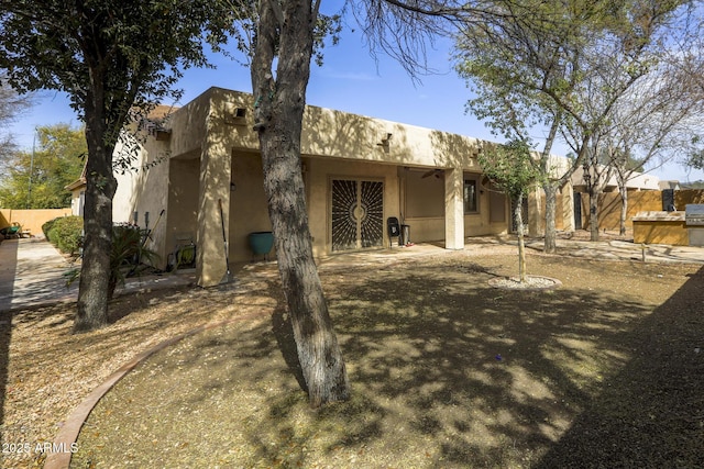 view of front of property featuring a patio area, fence, and stucco siding