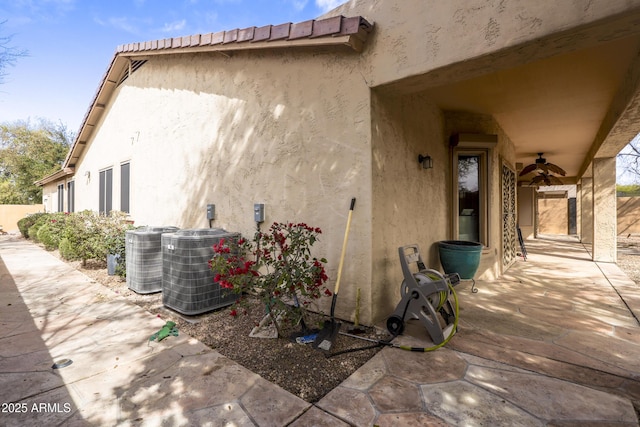 exterior space with stucco siding, ceiling fan, and central air condition unit