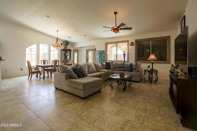 living room featuring ceiling fan with notable chandelier, plenty of natural light, and baseboards