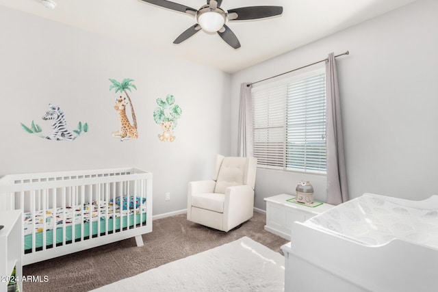 carpeted bedroom with ceiling fan and a crib