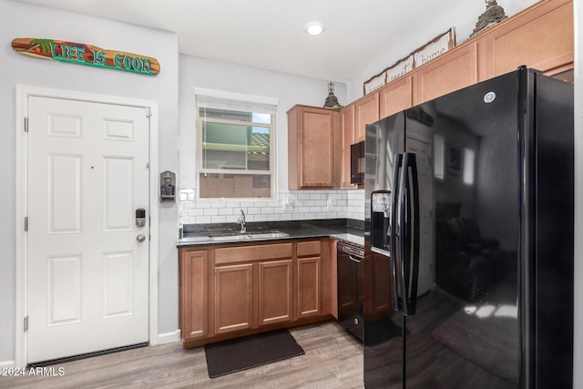 kitchen with black appliances, light hardwood / wood-style floors, sink, and backsplash