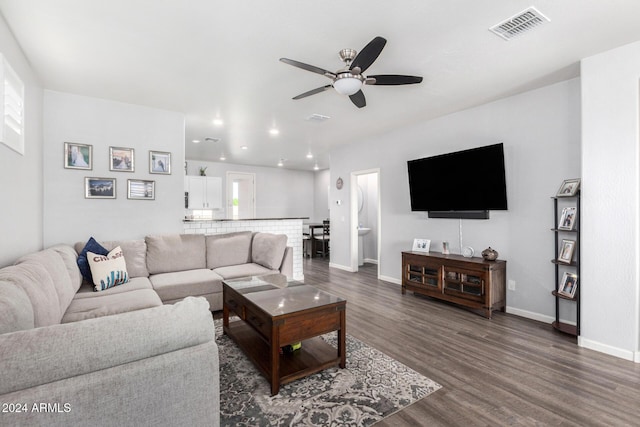 living room featuring ceiling fan and dark wood-type flooring