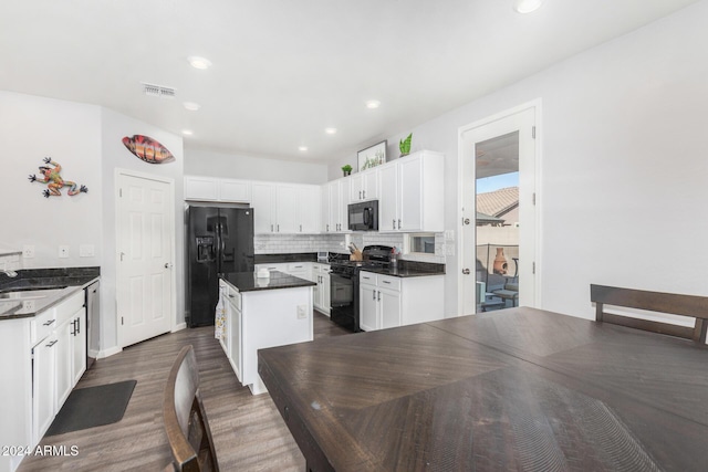 kitchen featuring dark hardwood / wood-style flooring, white cabinetry, a kitchen island, and black appliances