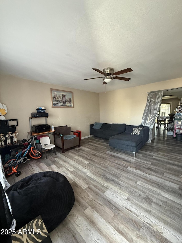 living room featuring ceiling fan, wood-type flooring, and a textured ceiling