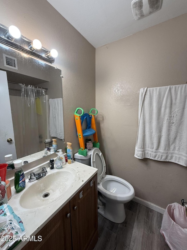 bathroom featuring vanity, hardwood / wood-style flooring, a shower with curtain, and toilet