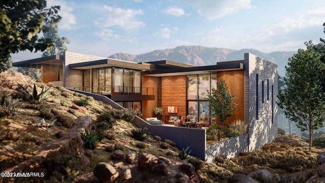 view of front of home with a mountain view, a balcony, and fence