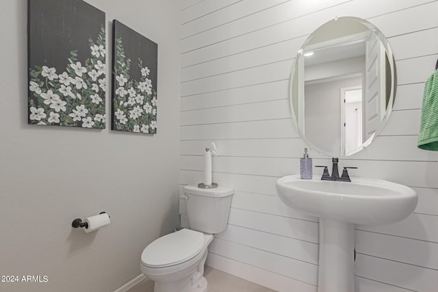 half bath featuring wood walls and toilet