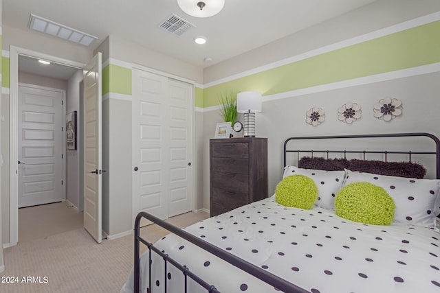 bedroom with a closet, visible vents, and light carpet