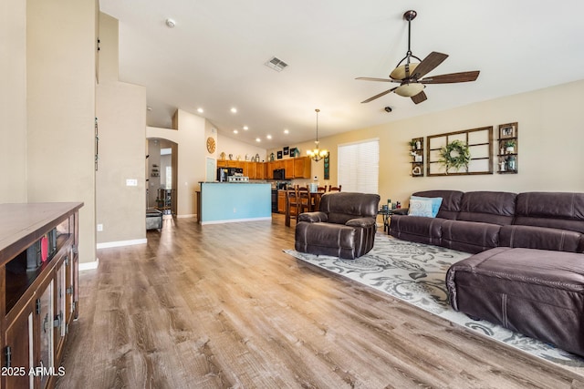 21604 E Calle De Flores, Queen Creek, AZ 85142 - living room with vaulted ceiling, ceiling fan with notable chandelier, baseboards, arched walkways, and wood finished floors