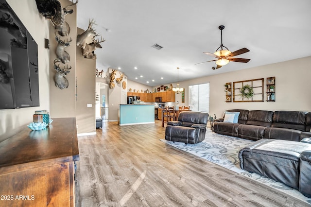 21604 E Calle De Flores, Queen Creek, AZ 85142 - living area featuring vaulted ceiling, ceiling fan with notable chandelier, arched walkways, light wood-style floors, and visible vents