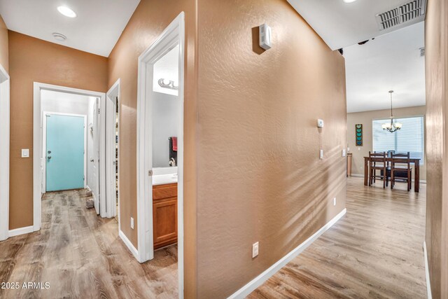 21604 E Calle De Flores, Queen Creek, AZ 85142 - corridor featuring baseboards, visible vents, light wood-style floors, a textured wall, and an inviting chandelier