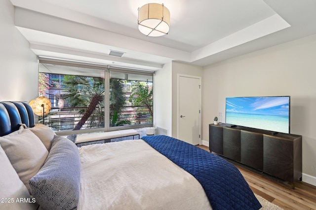 bedroom featuring light wood finished floors, visible vents, and baseboards