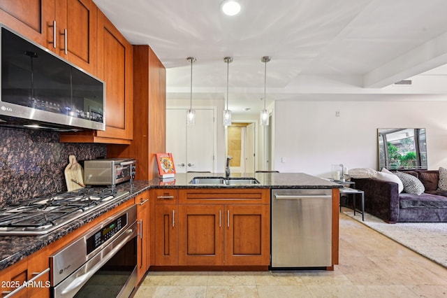 kitchen featuring appliances with stainless steel finishes, open floor plan, a peninsula, pendant lighting, and a sink