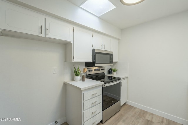 kitchen with white cabinets, light wood-type flooring, and appliances with stainless steel finishes