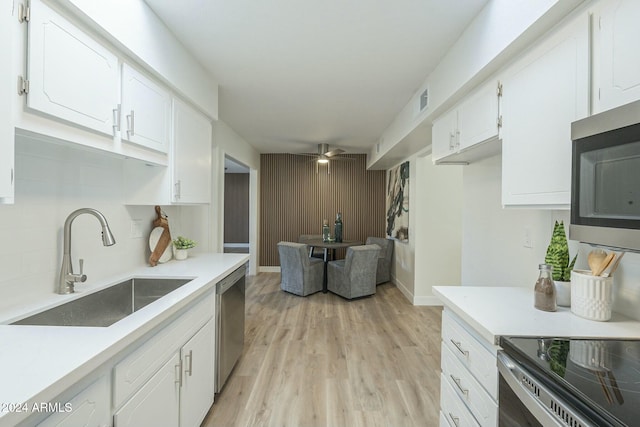 kitchen featuring backsplash, sink, light hardwood / wood-style floors, white cabinetry, and stainless steel appliances