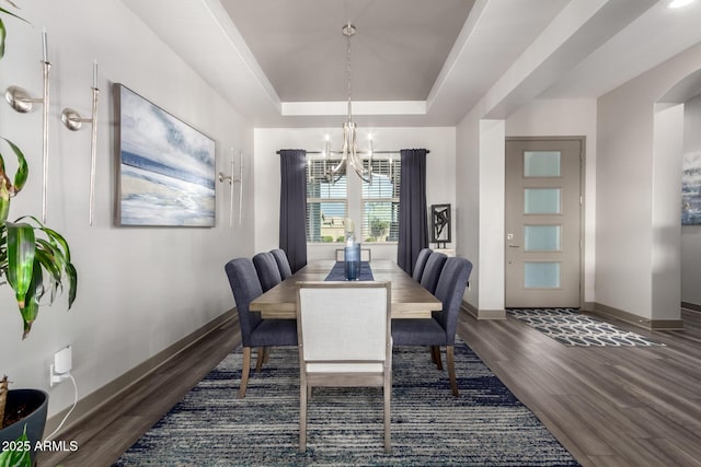 dining area with a tray ceiling, baseboards, a notable chandelier, and wood finished floors