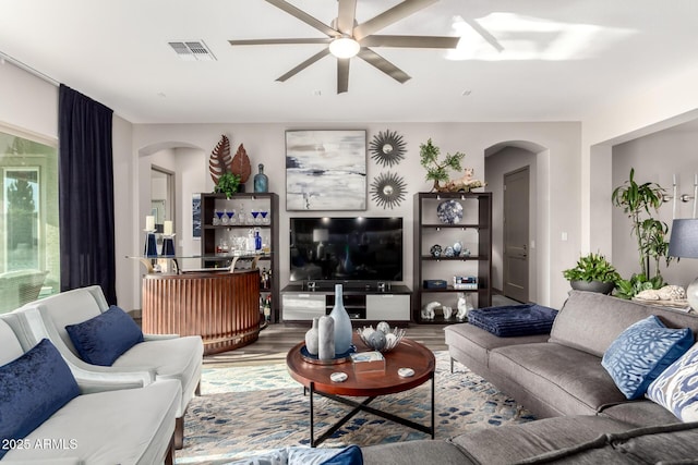 living area featuring visible vents, wood finished floors, arched walkways, and ceiling fan