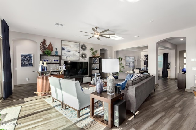 living area featuring visible vents, wood finished floors, bar, a ceiling fan, and arched walkways