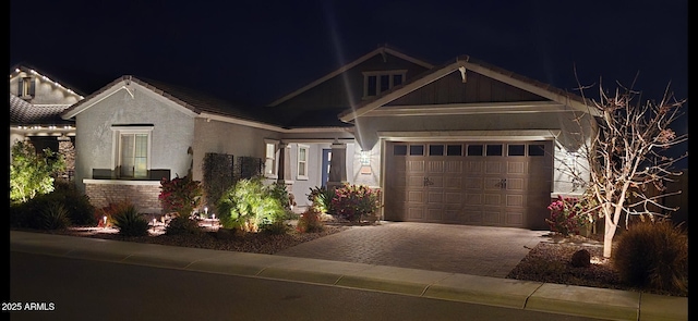 craftsman house with stucco siding, an attached garage, brick siding, and decorative driveway