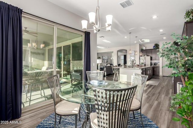 dining space featuring ceiling fan with notable chandelier, visible vents, wood finished floors, and recessed lighting