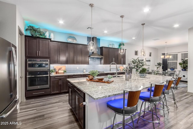 kitchen featuring a kitchen bar, stainless steel appliances, dark brown cabinetry, and decorative backsplash