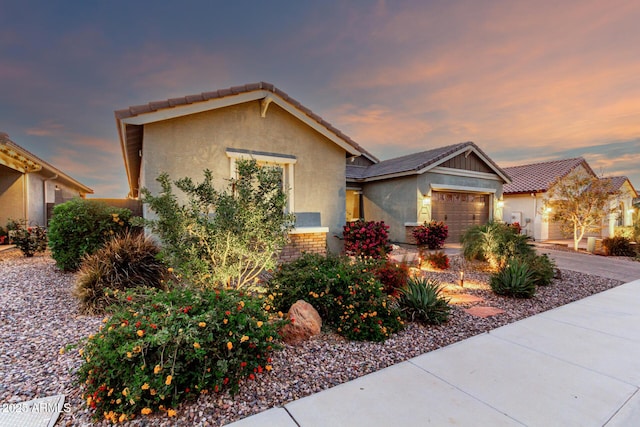 view of front of house featuring a tile roof, a garage, concrete driveway, and stucco siding