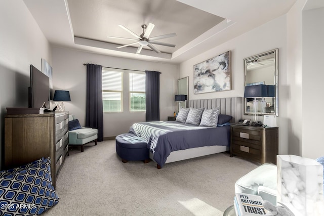 bedroom featuring a ceiling fan, a tray ceiling, and carpet