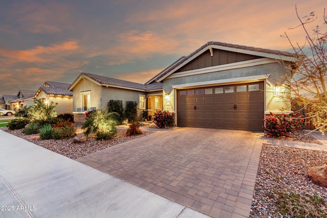 view of front of home featuring a tile roof, decorative driveway, an attached garage, and stucco siding