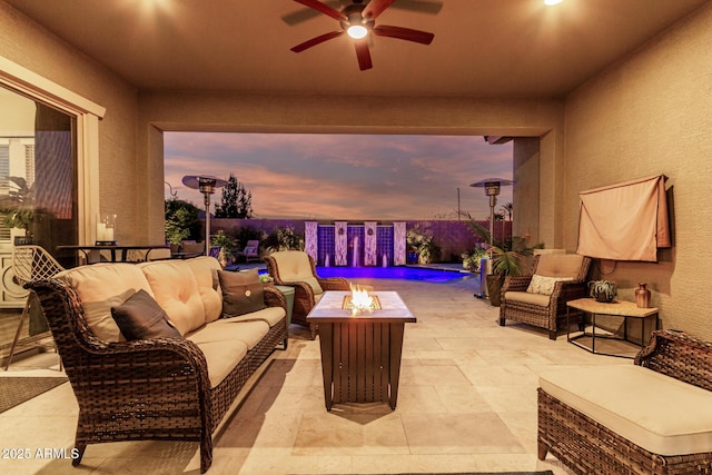 patio terrace at dusk with ceiling fan and an outdoor living space with a fire pit