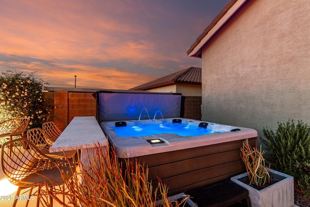 patio terrace at dusk with a hot tub and fence