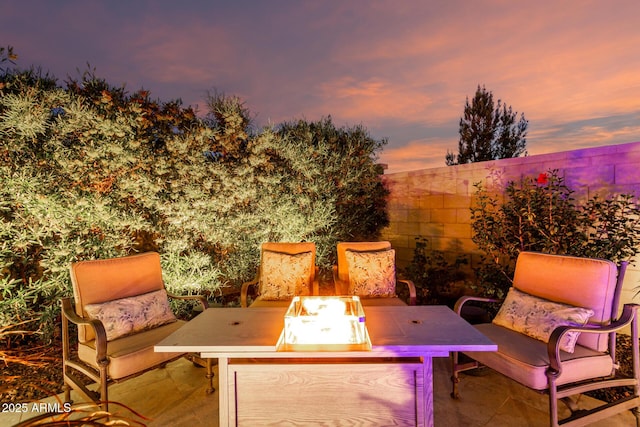 patio terrace at dusk featuring a fenced backyard and a fire pit