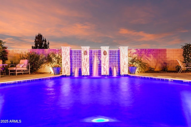 pool at dusk with a fenced in pool, fence, and a patio area
