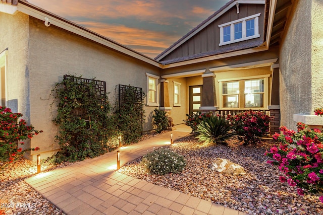 exterior entry at dusk with stucco siding and board and batten siding