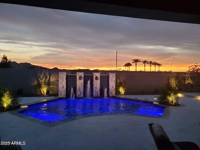 pool at dusk with a fenced in pool, fence, and a patio