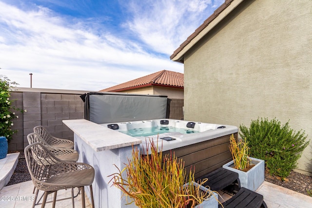 view of patio / terrace with a hot tub and fence
